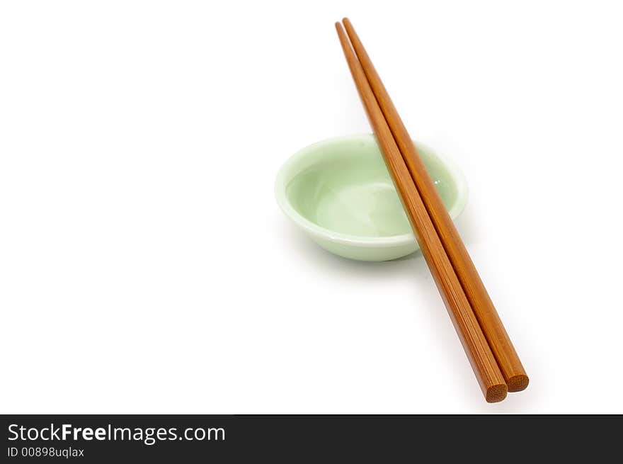 A pair of wooden chopsticks rest on a ceramic bowl. A pair of wooden chopsticks rest on a ceramic bowl.