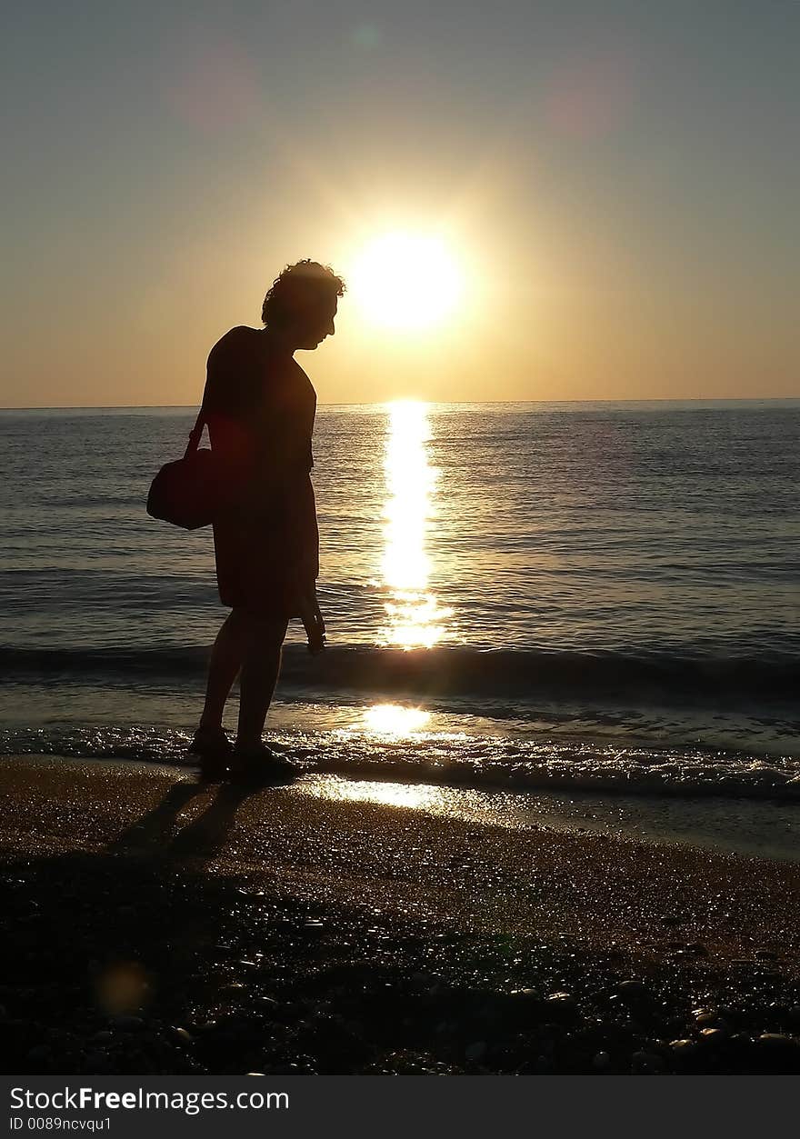 Sunrise silhouette of a photographer on the beach holding a tripod. Sunrise silhouette of a photographer on the beach holding a tripod