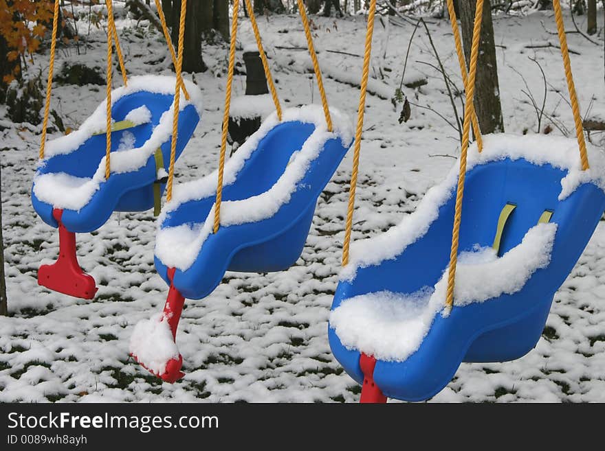 Three swings with fresh snow on them. Three swings with fresh snow on them