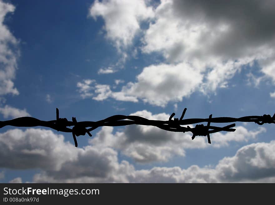 Barbed wire on a sunny day with blue sky, silhouette