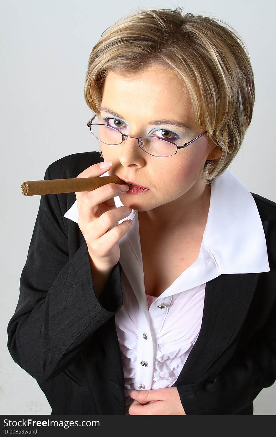 Blond business woman smoking a cigar in front of a grey background