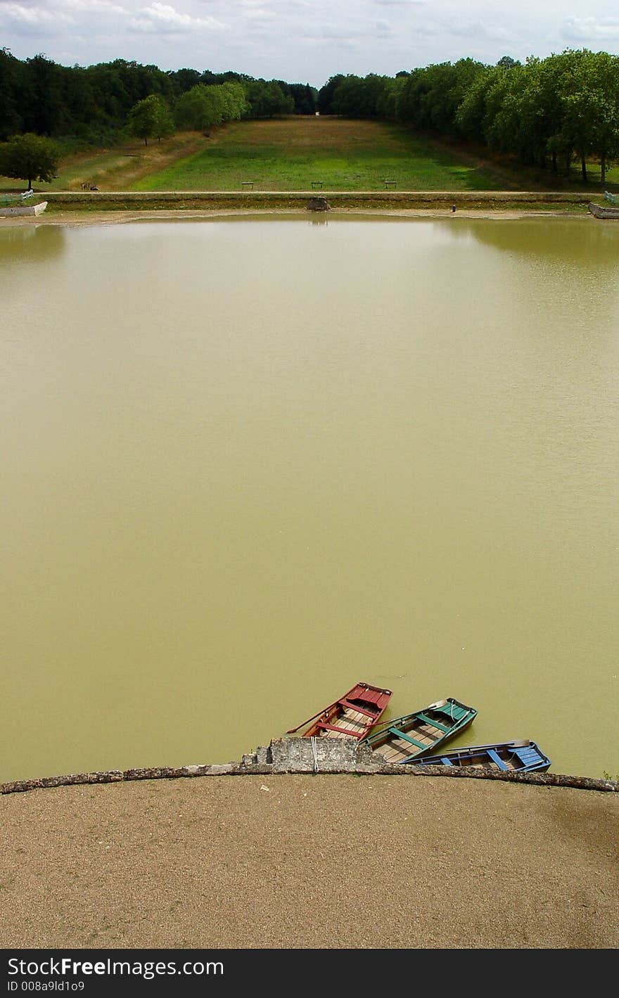 Three cute rowboats in mismatched colours on an artificial lake in the Loire valley. Three cute rowboats in mismatched colours on an artificial lake in the Loire valley