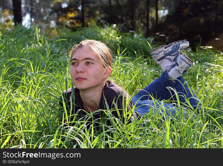 The joyful girl has a rest in a grass. The joyful girl has a rest in a grass