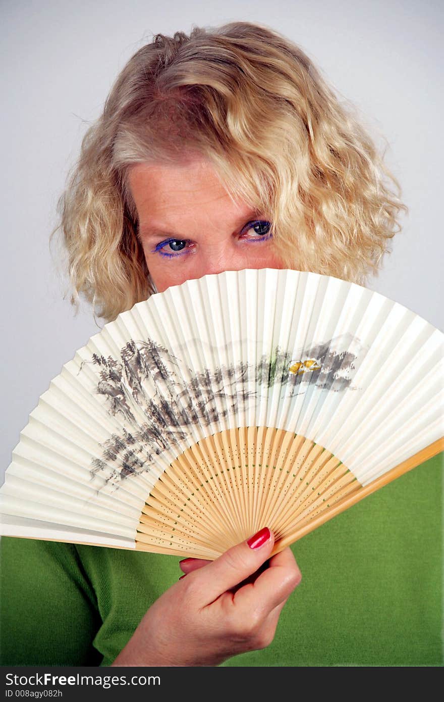 A self-confident, middle-aged woman holding an original japanese folding fan with filigree pattern. A self-confident, middle-aged woman holding an original japanese folding fan with filigree pattern.