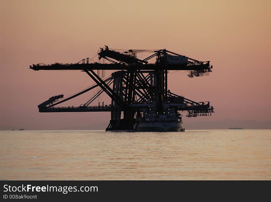 Large ship transporting dock loading machinery during a sunset. Large ship transporting dock loading machinery during a sunset.