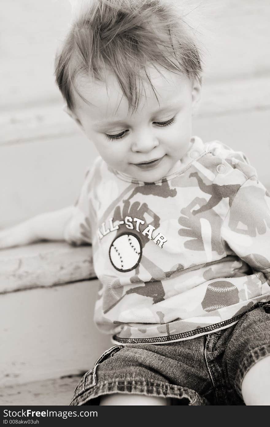 Black and white infant boy sitting on stairs with wind  blowing