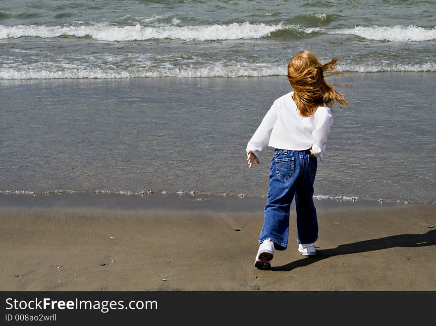 Small red-haired girl playing on the beach - windy day. Small red-haired girl playing on the beach - windy day.