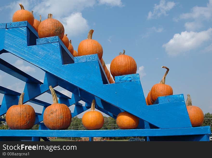 Orange pumpkins lined up on blue stairs. Recently harvested at a local farm and ready for sale. Orange pumpkins lined up on blue stairs. Recently harvested at a local farm and ready for sale.