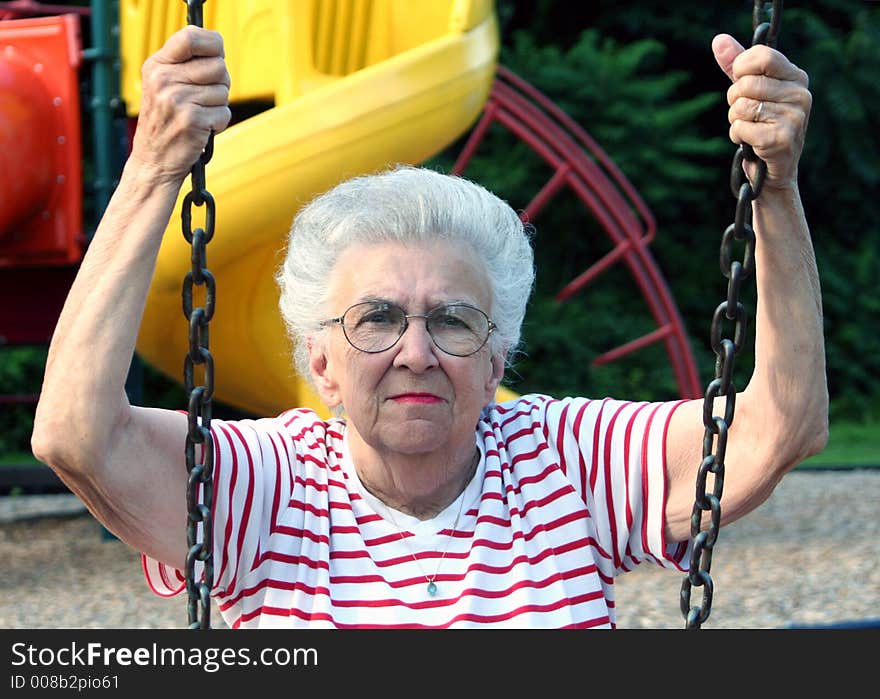 Senior citizen woman sitting on a playground swing. Senior citizen woman sitting on a playground swing.