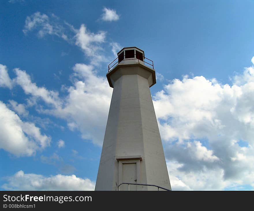 A lighthouse stands tall with clouds in the background. A lighthouse stands tall with clouds in the background