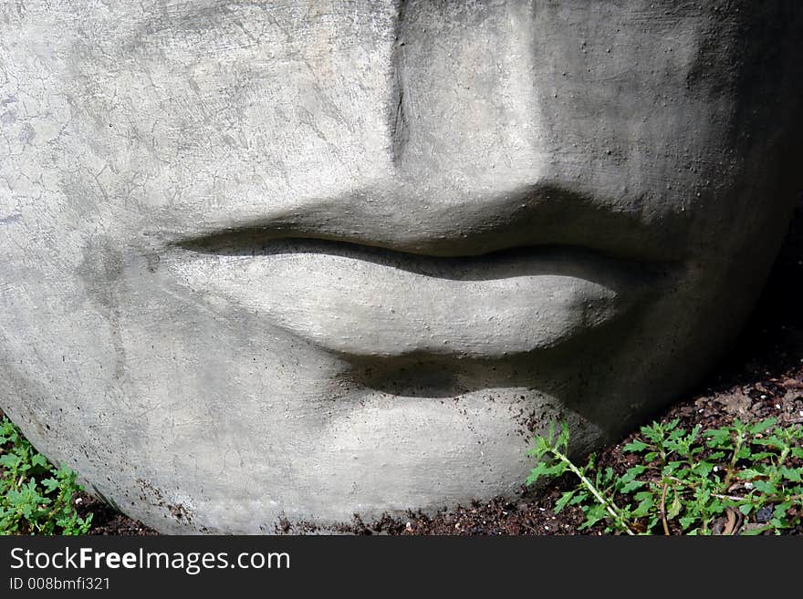 Detail of head sculpture laying in the dirt. Detail of head sculpture laying in the dirt