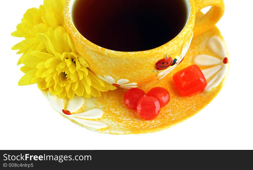 Yellow cup, chrysanthemums and sweets over white. Yellow cup, chrysanthemums and sweets over white