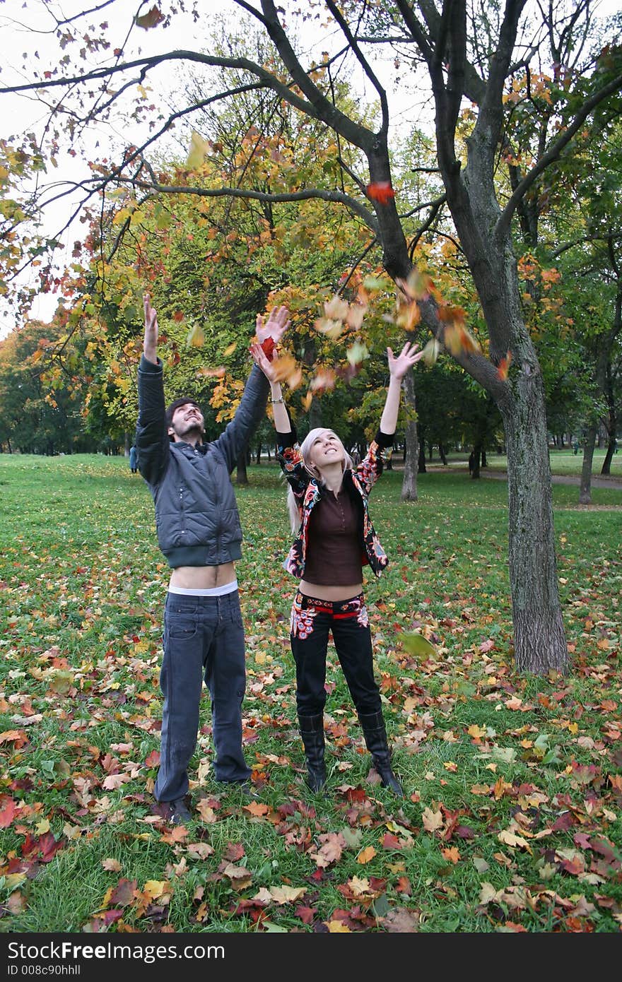 Autumn couple throw maple leaves