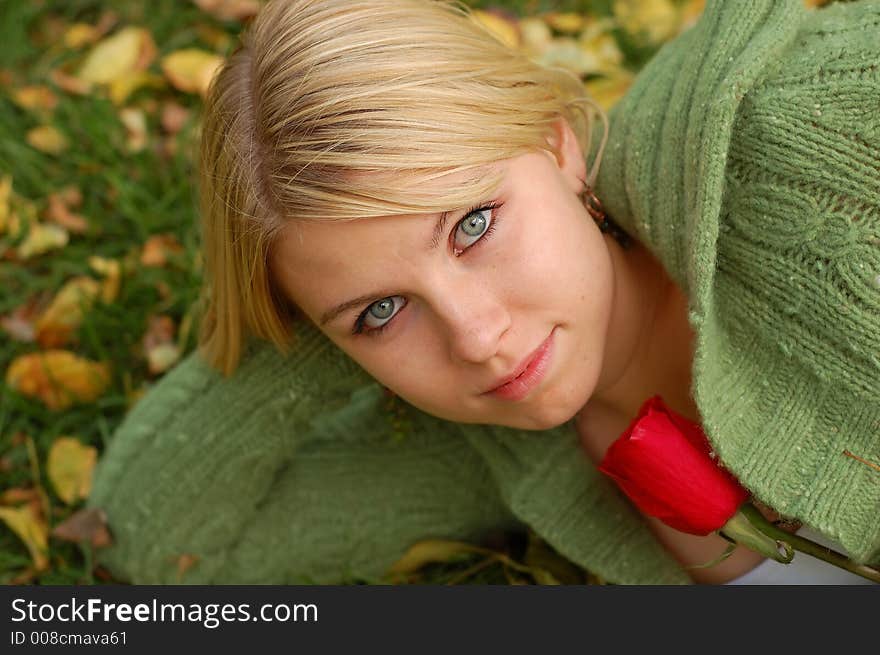 Beautiful girl holding red rose on bed of fall leaves. Beautiful girl holding red rose on bed of fall leaves.