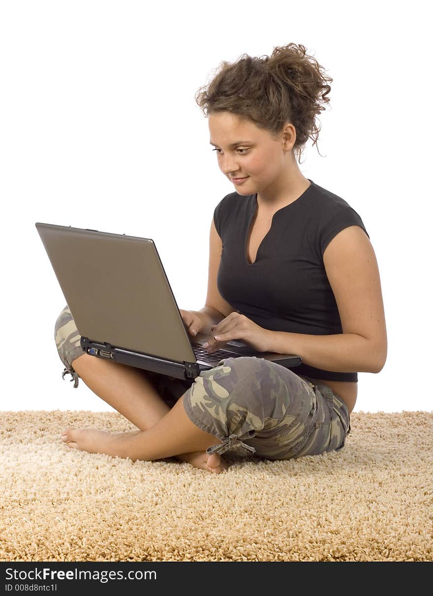 Isolated on white female teenager sitting on the carpet with laptop