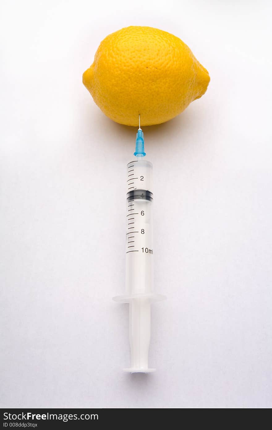 A bright yellow lemon being injected with a clear syringe. Illustrating food safety issues, Genetic engineering, and health. A bright yellow lemon being injected with a clear syringe. Illustrating food safety issues, Genetic engineering, and health.