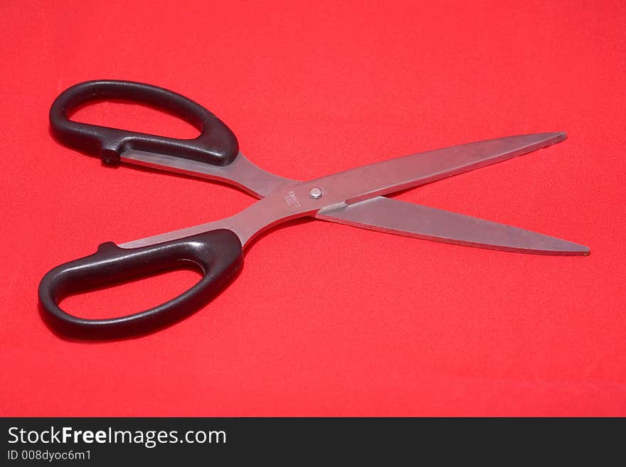 Open scissors isolated in red background