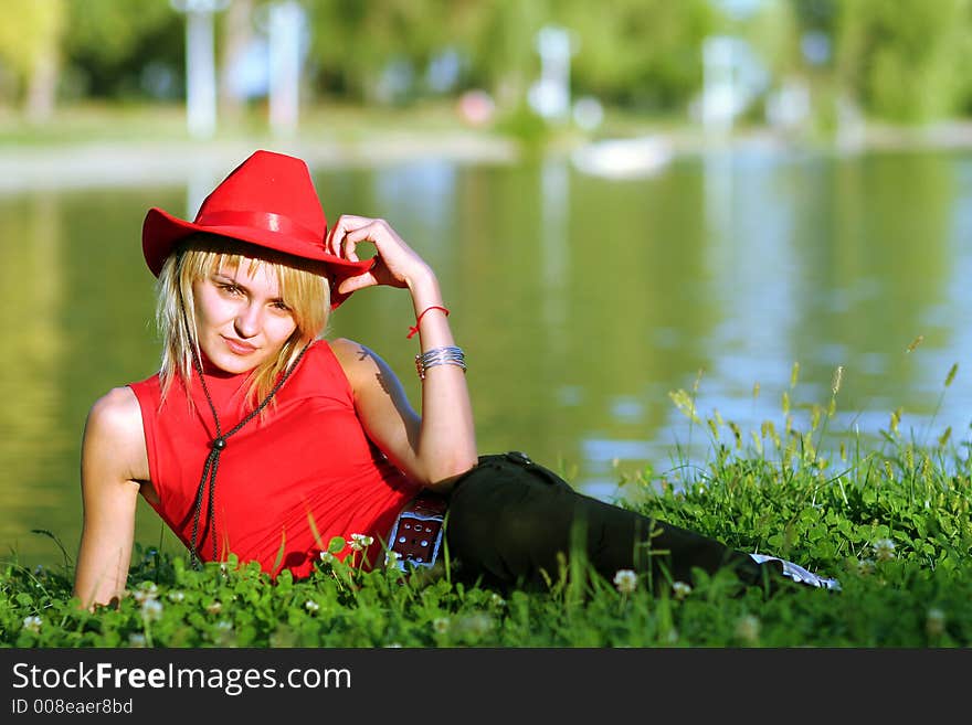 Beautiful sexy blonde cowgirl in the countryside with red hat