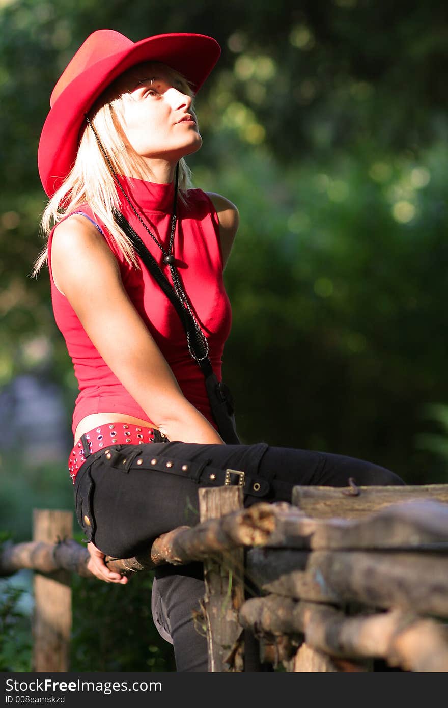 Beautiful sexy blonde cowgirl in the countryside with red hat