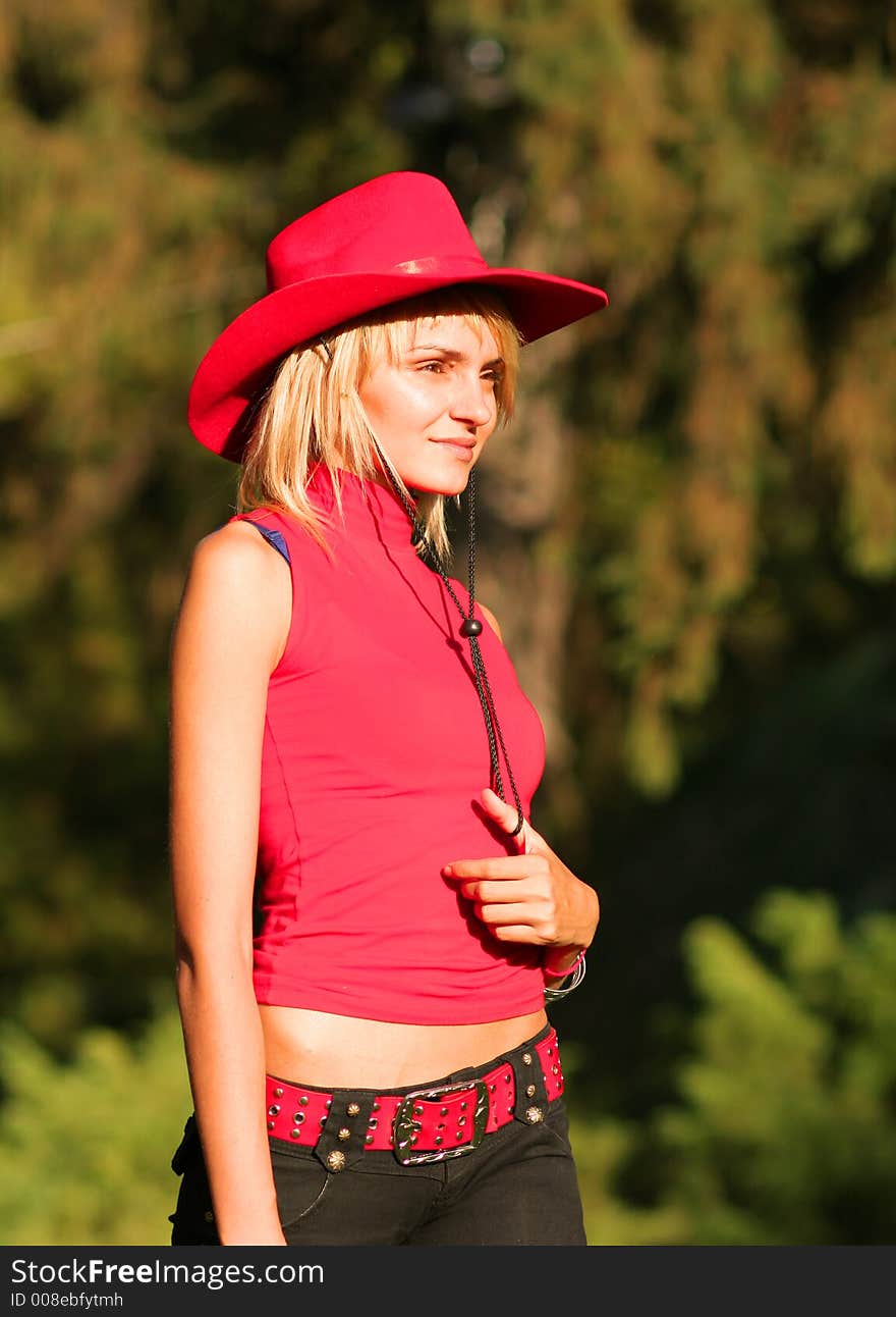 Beautiful sexy blonde cowgirl in the countryside with red hat