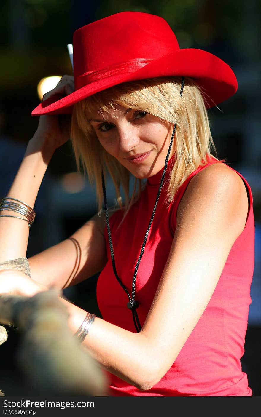 Beautiful sexy blonde cowgirl in the countryside with red hat