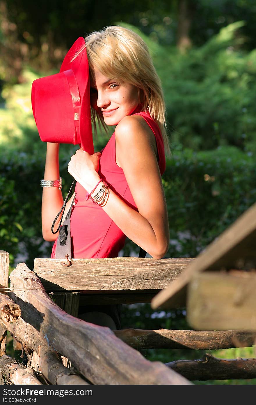 Beautiful sexy blonde cowgirl in the countryside with red hat