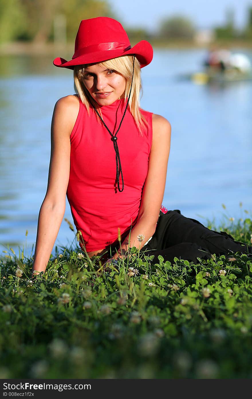 Beautiful sexy blonde cowgirl in the countryside with red hat