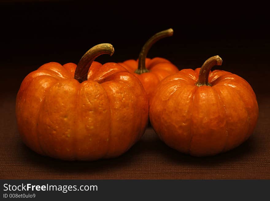 Three pumpkins against a dark background. Three pumpkins against a dark background