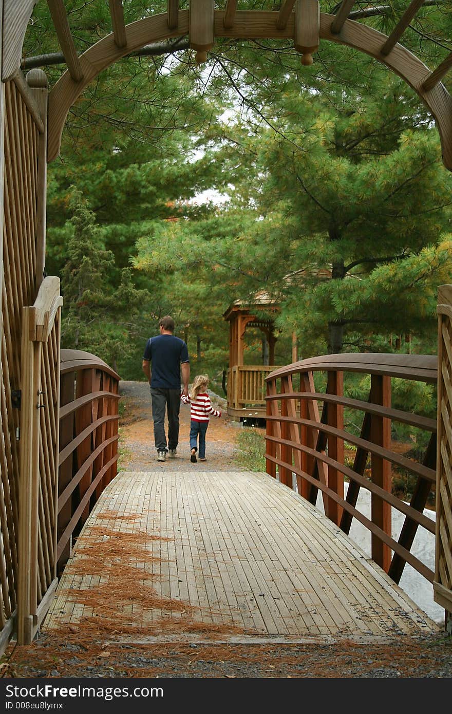 Father and child holding hands walking over bridge. Father and child holding hands walking over bridge.