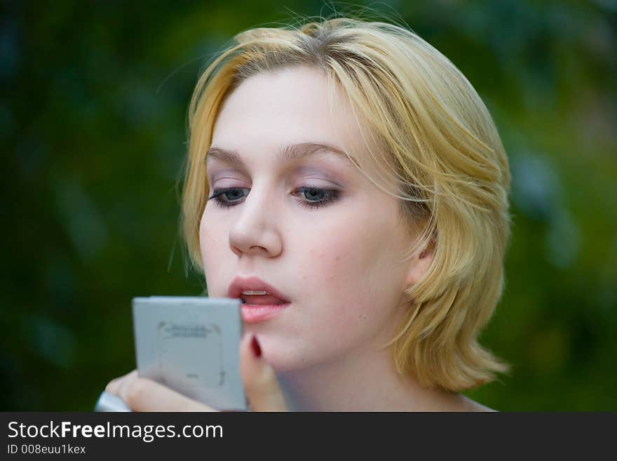 Beautiful Yong Blonde Girl with Blue Eyes Putting on Makeup