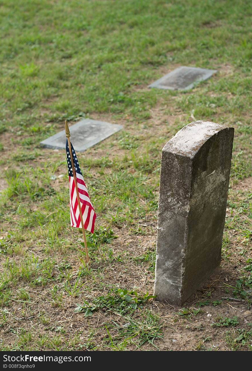 A tombstone or grave marker with an United States of America US Flag. A tombstone or grave marker with an United States of America US Flag.