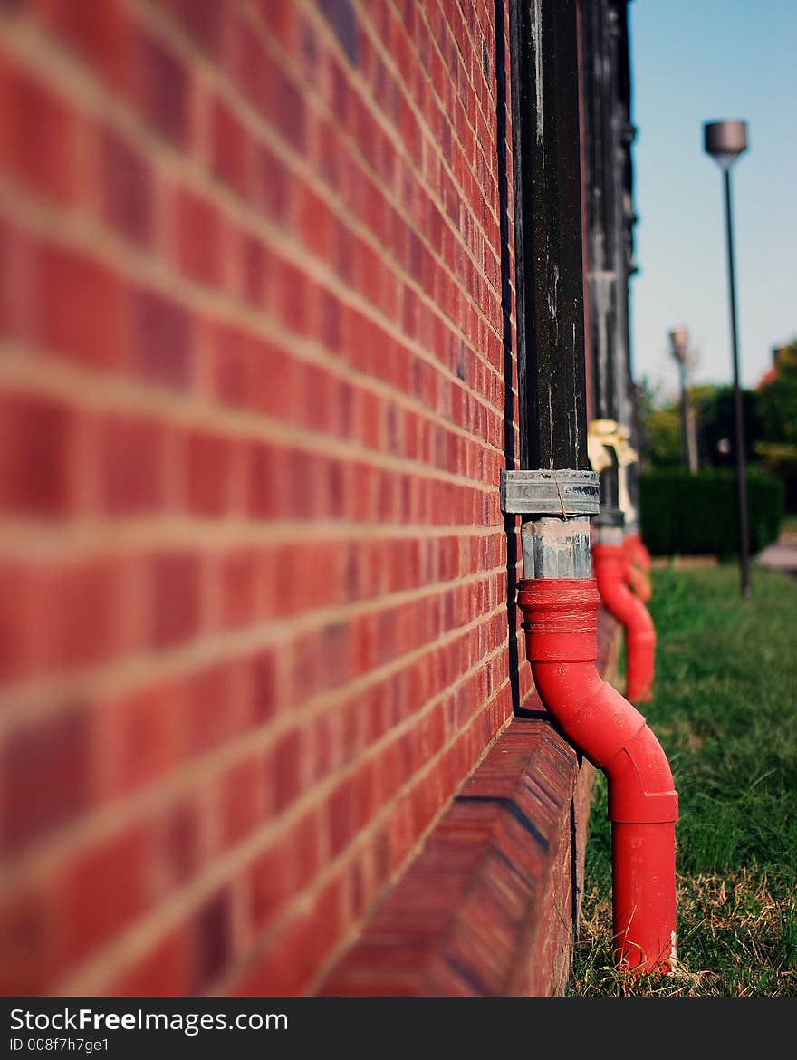 Pipes on a red brick wall with some sky background