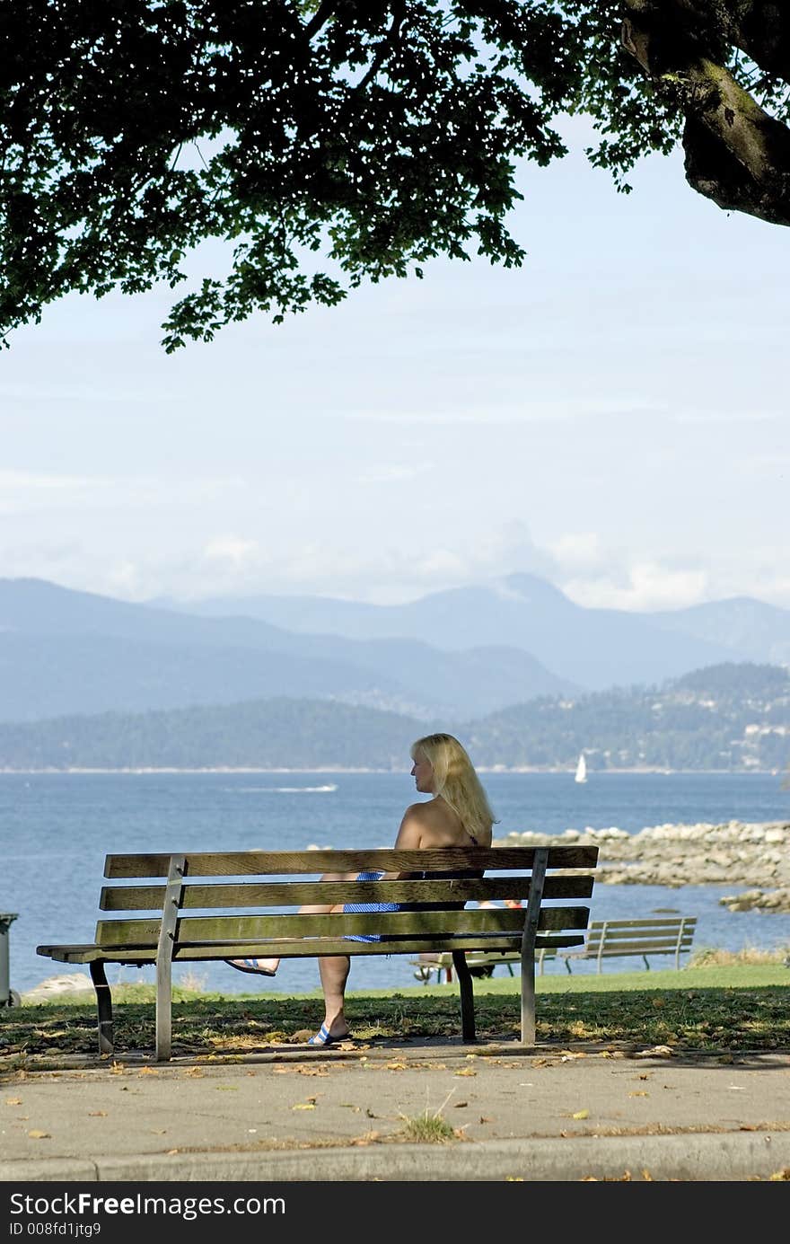 A lady sitting on a bench gazing out to sea. A lady sitting on a bench gazing out to sea