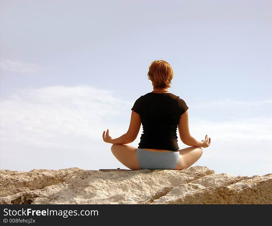 Woman in black meditating on rock. Woman in black meditating on rock