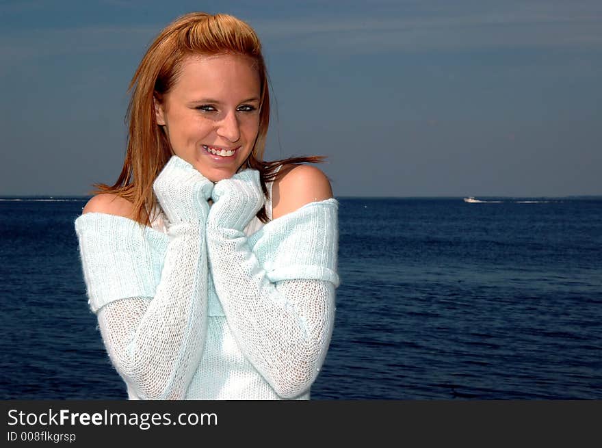 A pretty teen keeping warm in a sweater by the ocean. A pretty teen keeping warm in a sweater by the ocean