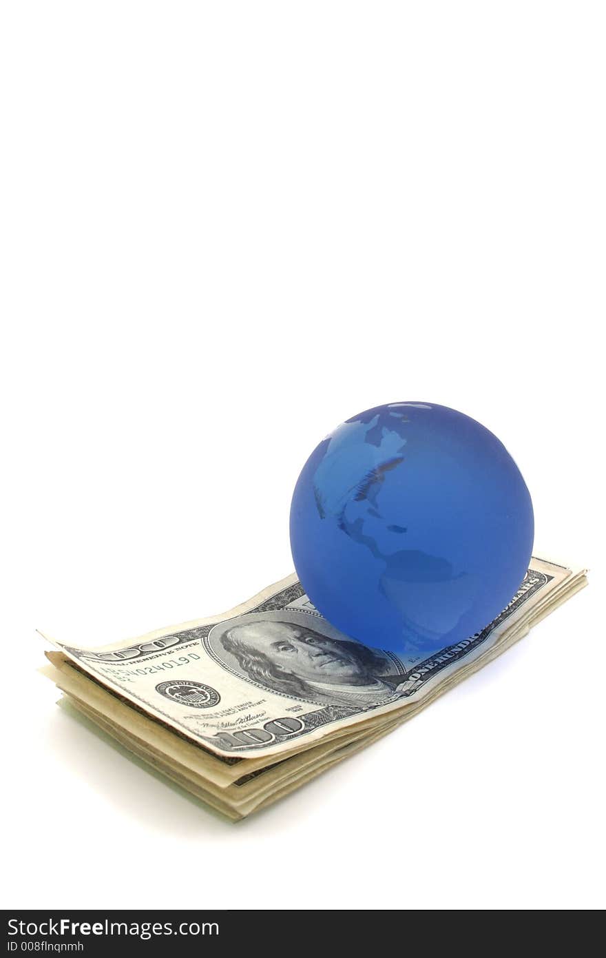 Blue glass globe paper weight on a stack of US money. Blue glass globe paper weight on a stack of US money