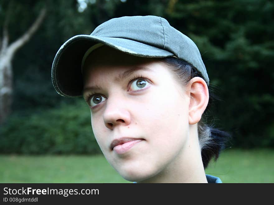 Young woman with cap looking up with nature background