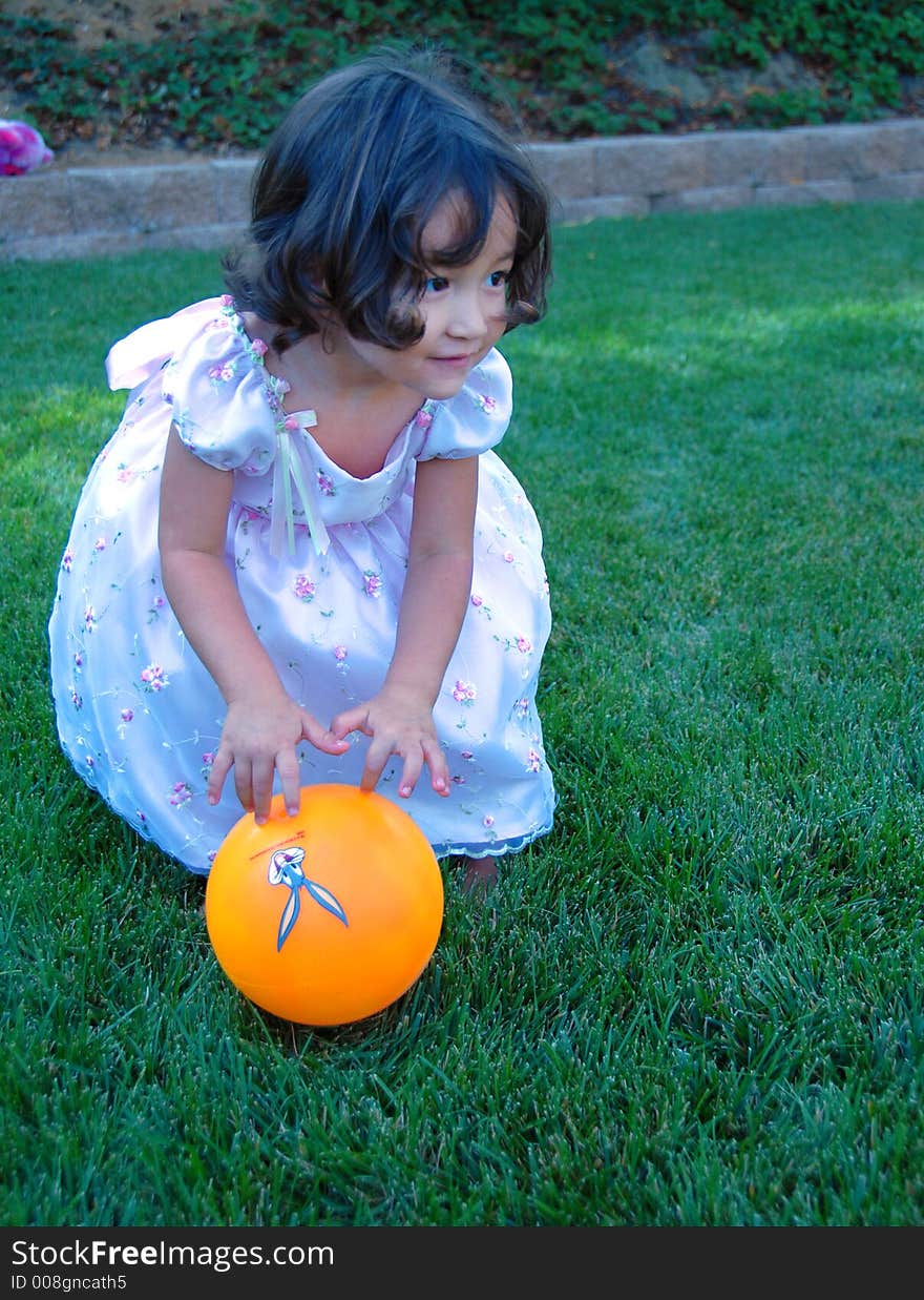 Little girl in beautiful dress is playing ball on the grass. Little girl in beautiful dress is playing ball on the grass