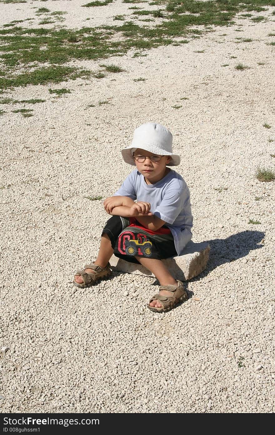 A young boy sits on the stone. A young boy sits on the stone