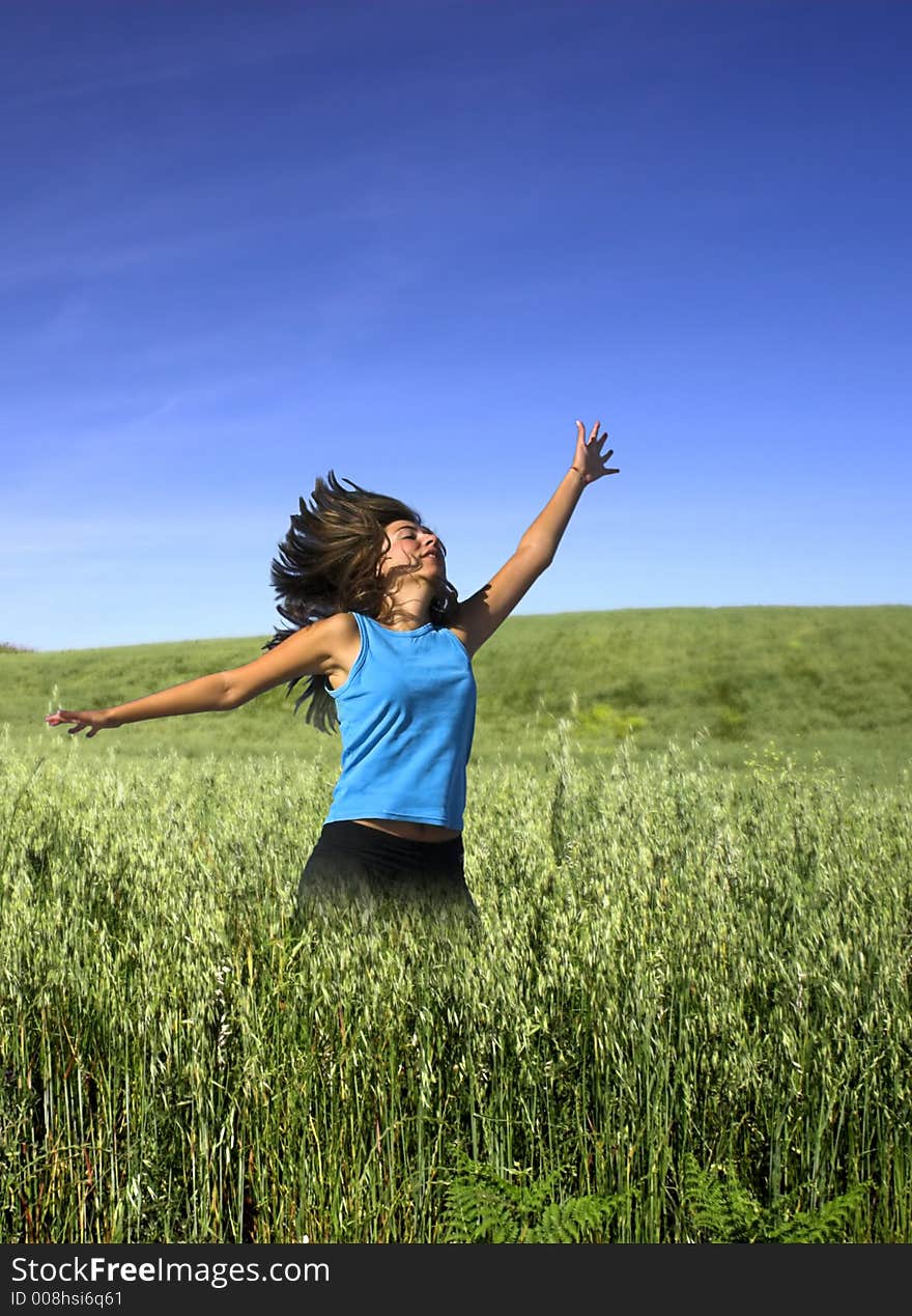 Young active woman jumping on a green field