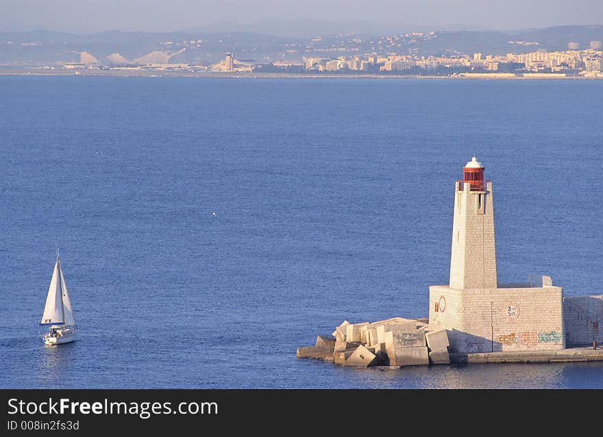 Boat at the entrance of Nice port, in french riviera, europe, part of the city in the background. Boat at the entrance of Nice port, in french riviera, europe, part of the city in the background