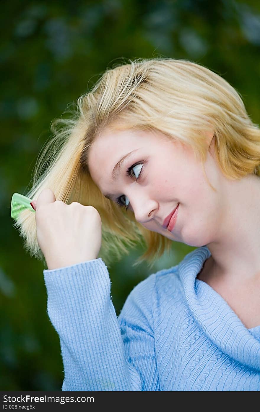 Beautiful Yong Blonde Girl with Blue Eyes Combing her Hair