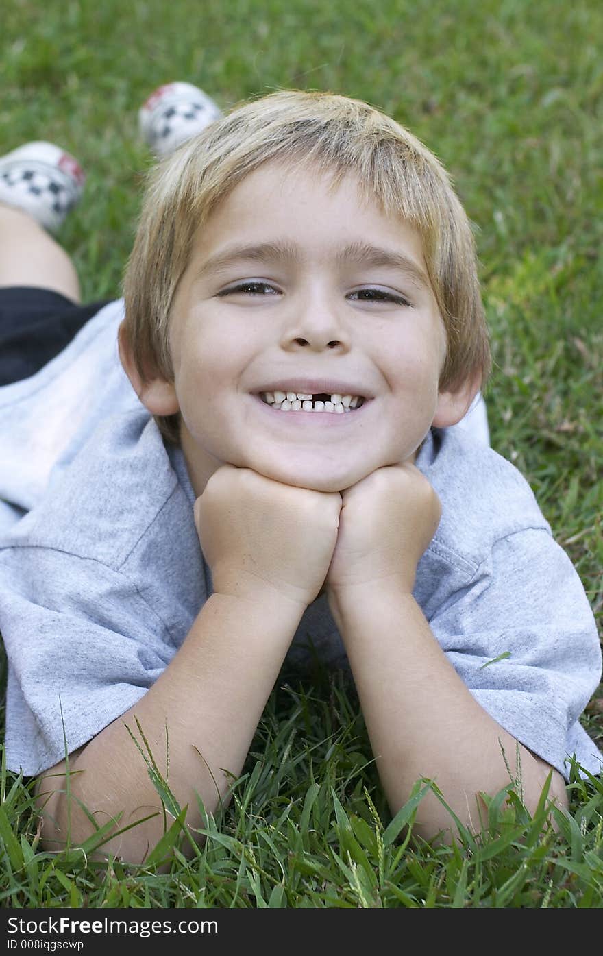 Young boy on grass smiling. Young boy on grass smiling