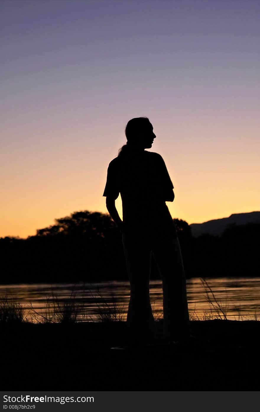 Woman standing on bank of Zambezi river in zambia during sunset. Woman standing on bank of Zambezi river in zambia during sunset