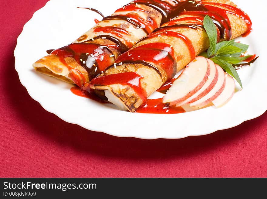 Pancake rolls stuffed with whipped cream and covered with strawberry jam coating pralin�e decorations. Pancake rolls stuffed with whipped cream and covered with strawberry jam coating pralin�e decorations