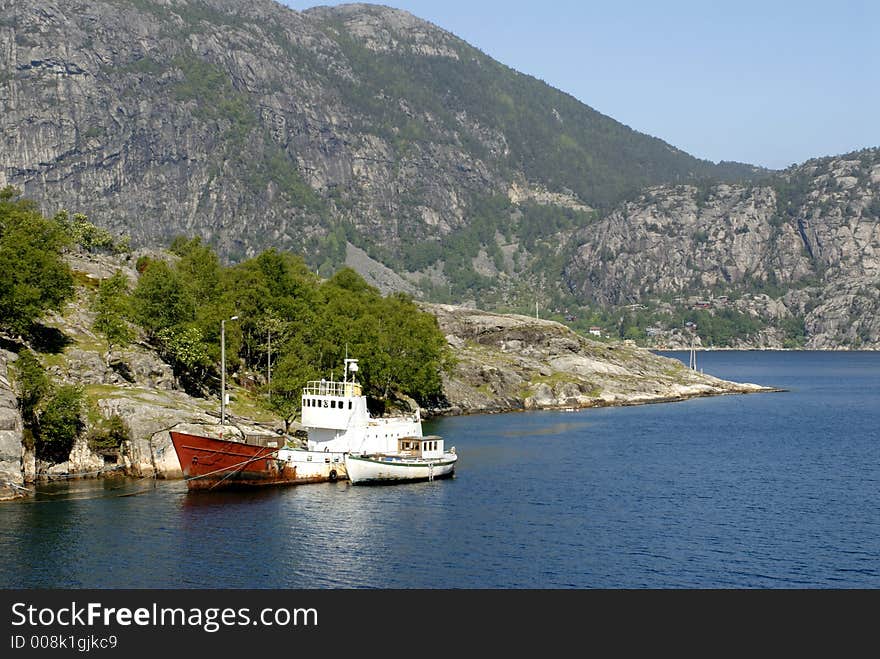 Picture of boat in fjord near rocky coast.