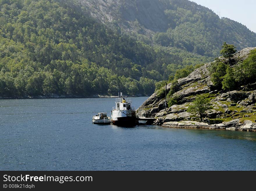 Picture of boat in fjord near rocky coast.