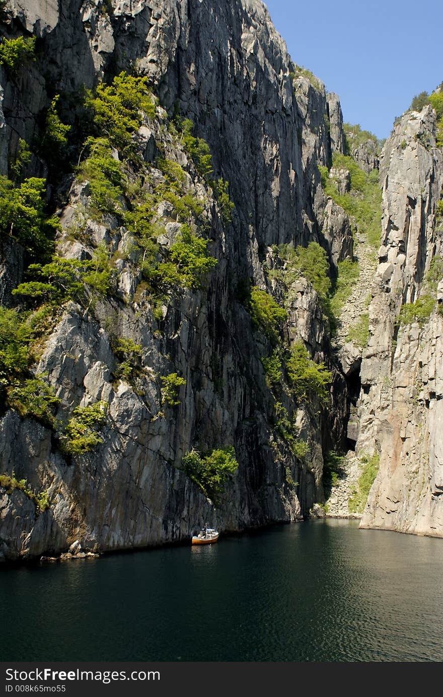 Picture of boat in fjord near rocky coast.