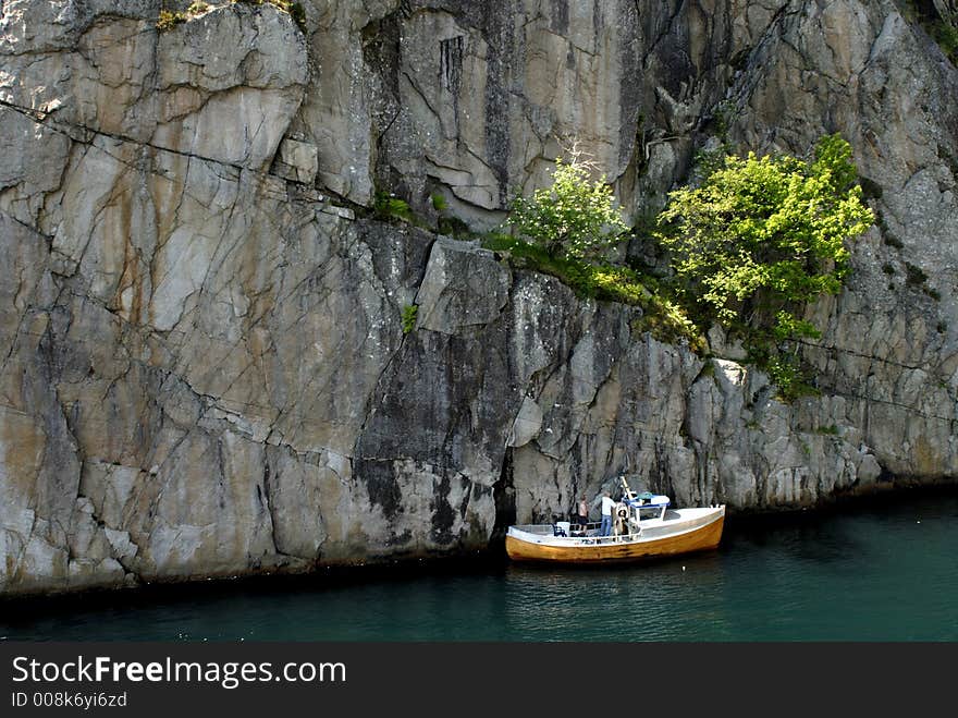 Picture of boat in fjord near rocky coast.