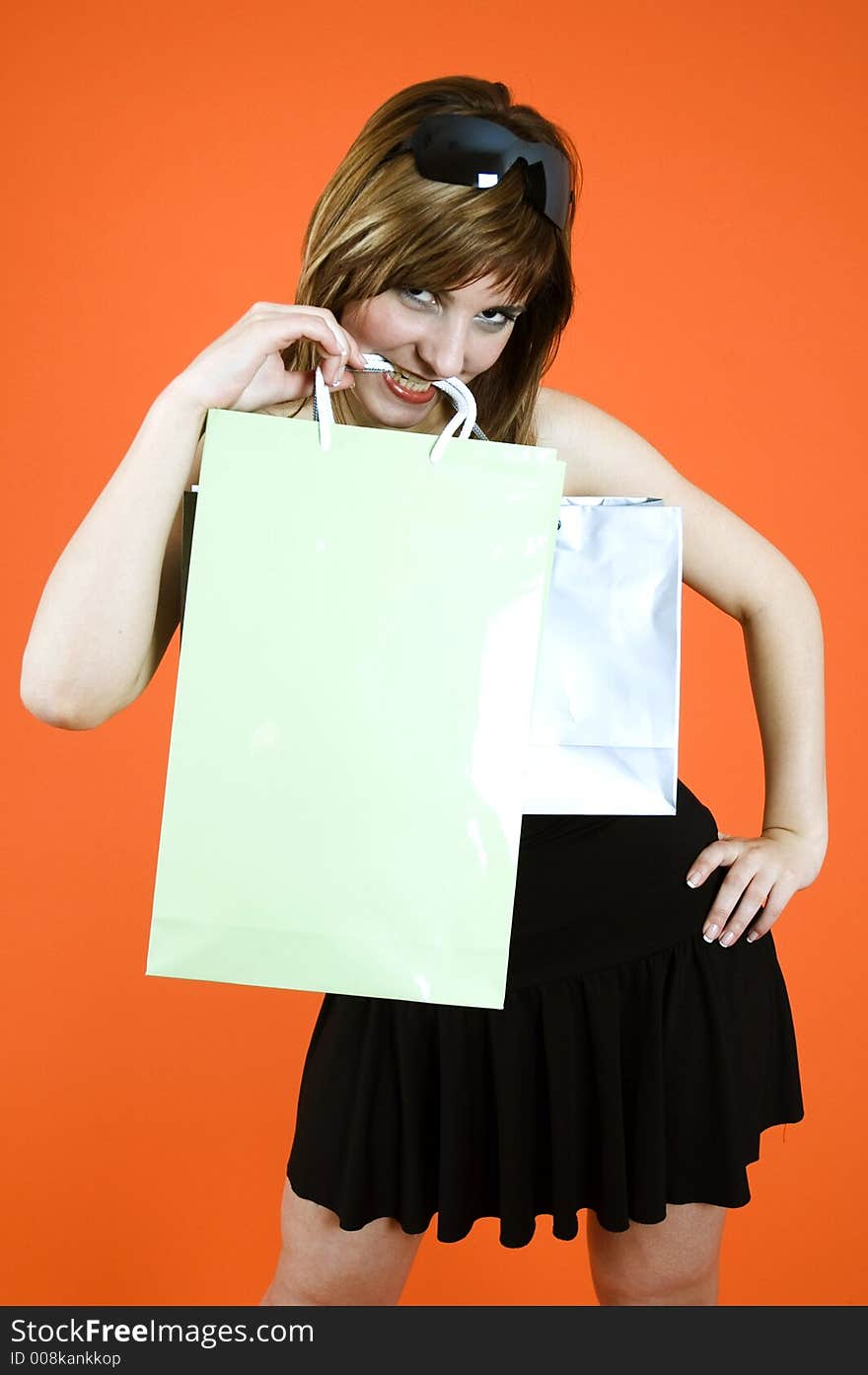 Brown haired young woman holds some shopping bags and a debit card - shopping addiction. Brown haired young woman holds some shopping bags and a debit card - shopping addiction